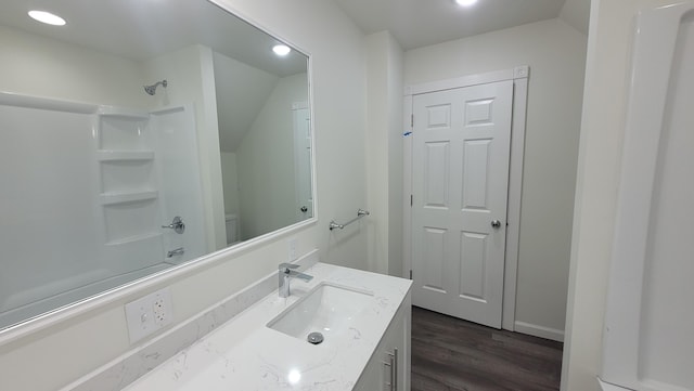 full bathroom with hardwood / wood-style floors, vanity, lofted ceiling, toilet, and shower / bathtub combination