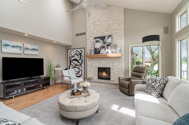 living room with a fireplace, ceiling fan, hardwood / wood-style floors, and high vaulted ceiling