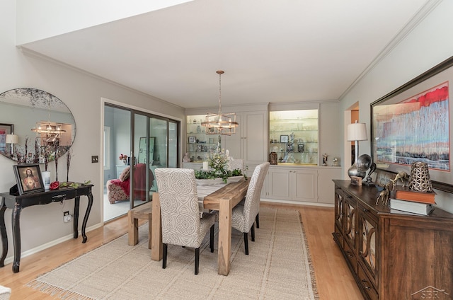 dining space with crown molding, light hardwood / wood-style flooring, and an inviting chandelier