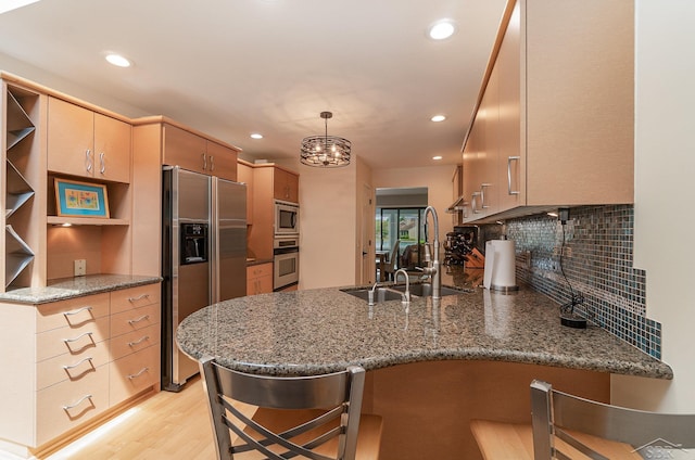 kitchen featuring kitchen peninsula, a kitchen breakfast bar, stainless steel appliances, stone countertops, and light hardwood / wood-style floors