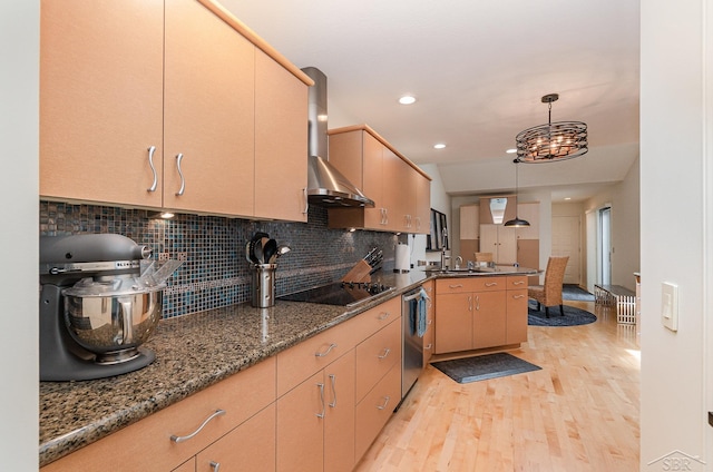 kitchen featuring wall chimney range hood, dark stone counters, pendant lighting, black electric cooktop, and light wood-type flooring