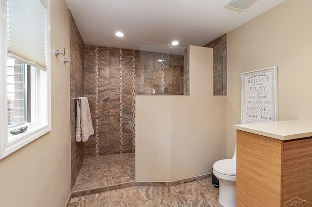 bathroom with tiled shower and toilet