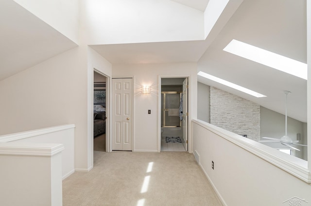 corridor with lofted ceiling with skylight and light carpet