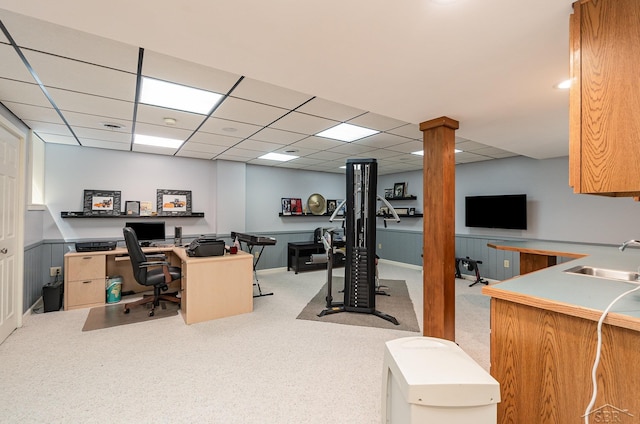 carpeted office with a drop ceiling and sink