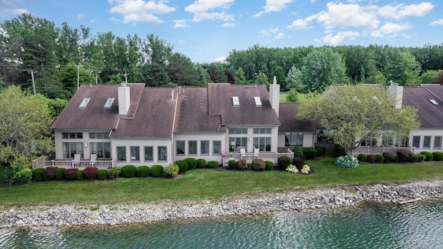 rear view of house with a lawn and a water view