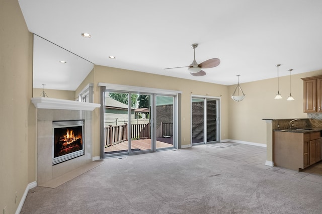 unfurnished living room featuring ceiling fan, light colored carpet, and sink