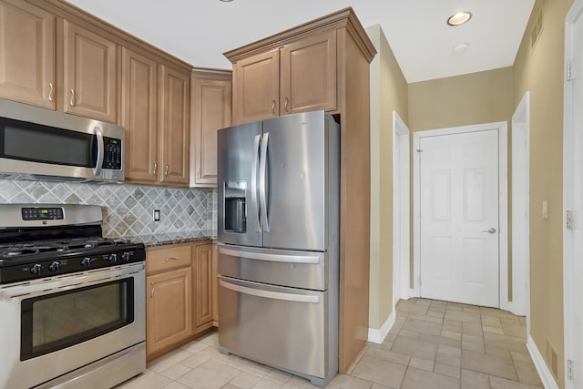 kitchen with appliances with stainless steel finishes, tasteful backsplash, and dark stone countertops