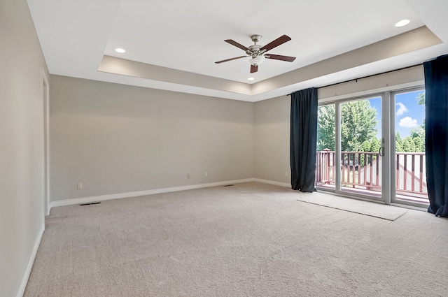 carpeted empty room featuring a raised ceiling and ceiling fan