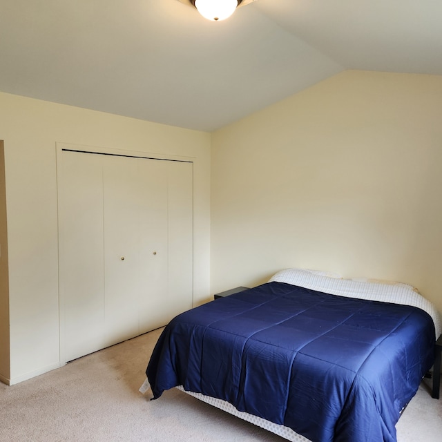 carpeted bedroom with a closet and lofted ceiling