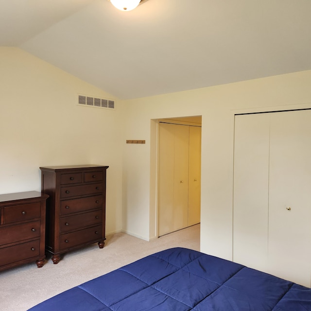 unfurnished bedroom featuring multiple closets, light carpet, and lofted ceiling