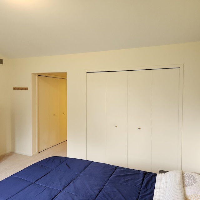 unfurnished bedroom with light colored carpet and two closets