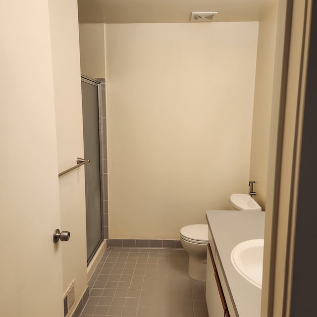 bathroom with tile patterned floors, a shower with door, vanity, and toilet