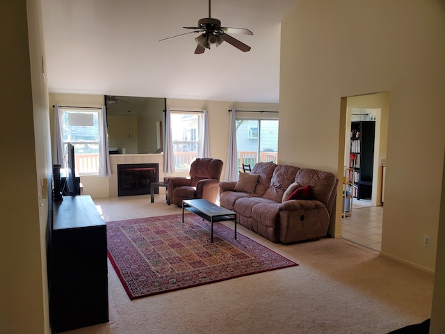 living room with ceiling fan, a fireplace, a towering ceiling, and light carpet