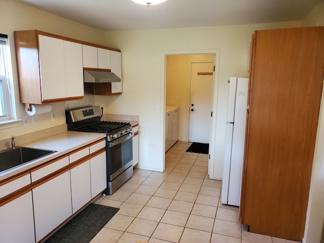 kitchen with gas range, white fridge, white cabinetry, and washer and clothes dryer