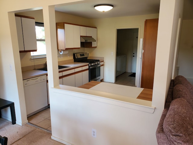 kitchen featuring white dishwasher, sink, independent washer and dryer, white cabinetry, and stainless steel range with gas stovetop