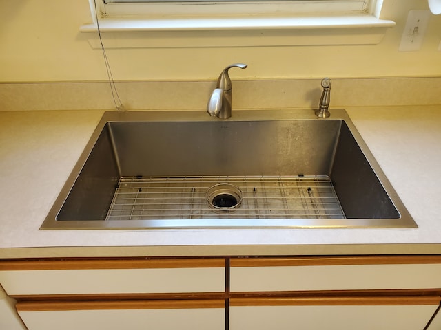 interior details with white cabinetry and sink