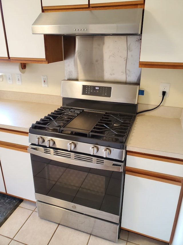 kitchen featuring white cabinetry, stainless steel range with gas cooktop, light tile patterned floors, and exhaust hood