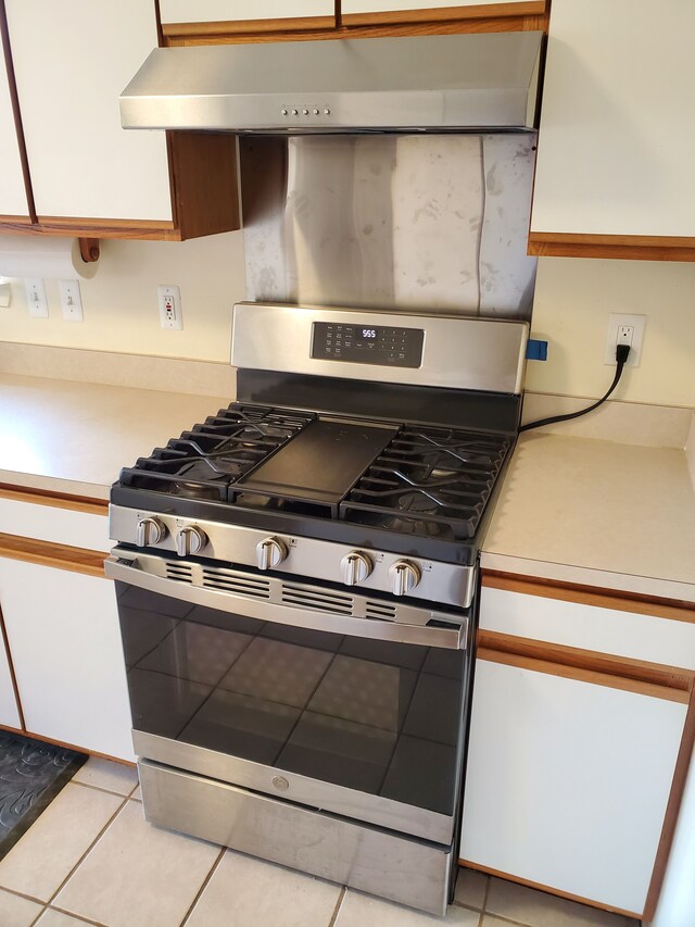 2233 Maplehurst Dr, Walled Lake, MI 48390 - kitchen with stainless steel range with gas stovetop, light countertops, under cabinet range hood, and light tile patterned floors