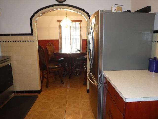 kitchen with stainless steel fridge, light parquet floors, and tile walls