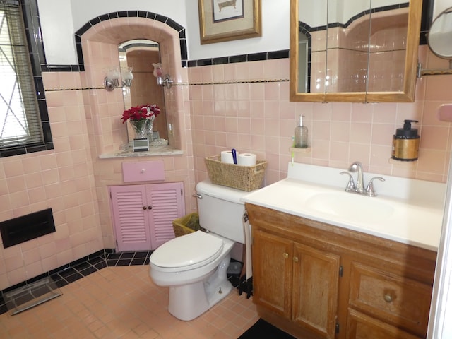 bathroom featuring tile patterned floors, vanity, toilet, and tile walls