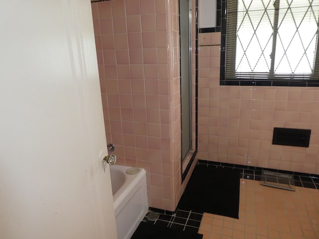 bathroom featuring tile patterned flooring, independent shower and bath, and tile walls