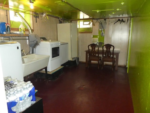 basement featuring independent washer and dryer, sink, and wooden walls