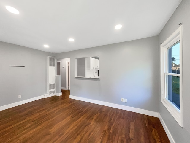 100 E Kalama Ave, Madison Heights, MI 48071 - empty room featuring dark wood-type flooring, baseboards, a heating unit, recessed lighting, and a sink