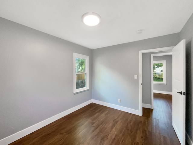 empty room with a wealth of natural light and dark hardwood / wood-style flooring