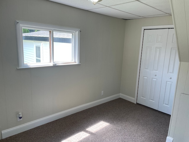 unfurnished bedroom featuring carpet, a paneled ceiling, and a closet