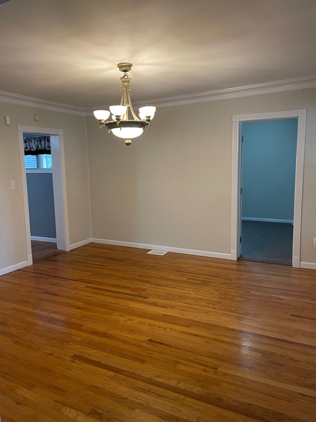 spare room with a notable chandelier, wood-type flooring, and ornamental molding