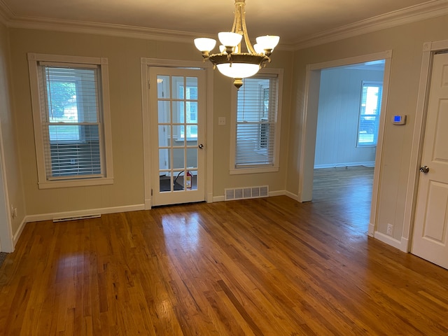 doorway to outside featuring crown molding, an inviting chandelier, a healthy amount of sunlight, and wood-type flooring