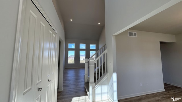 corridor with dark hardwood / wood-style floors and a high ceiling