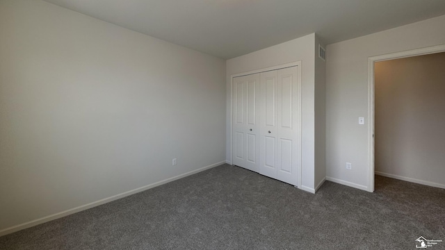 unfurnished bedroom with a closet and dark colored carpet