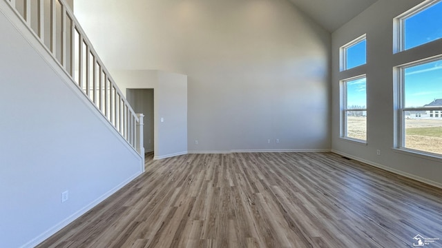 unfurnished living room featuring wood-type flooring and a towering ceiling