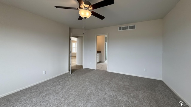 unfurnished bedroom featuring ceiling fan, light colored carpet, and ensuite bath