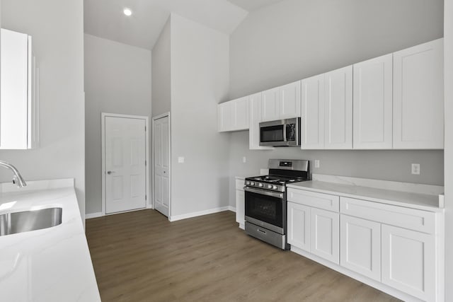 31433 Augusta Dr Unit 75, Romulus, MI 48174 - kitchen featuring appliances with stainless steel finishes, high vaulted ceiling, white cabinets, light wood-style floors, and light stone countertops
