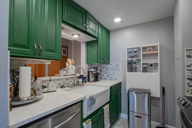 kitchen with backsplash, green cabinets, sink, light stone countertops, and appliances with stainless steel finishes