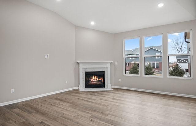 unfurnished living room featuring a fireplace, vaulted ceiling, and light wood-type flooring