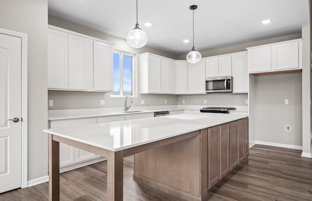 kitchen with white cabinetry, appliances with stainless steel finishes, a center island, and pendant lighting