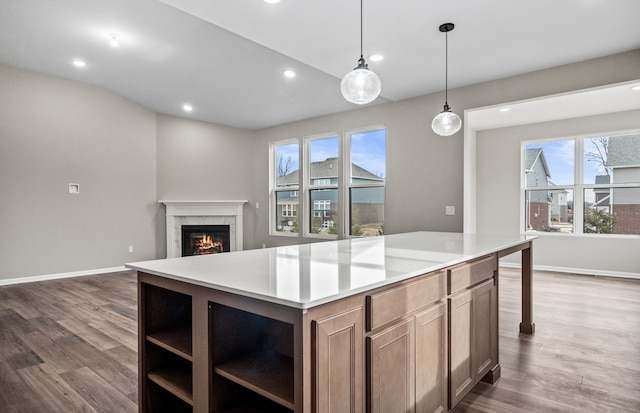 kitchen with pendant lighting, hardwood / wood-style floors, a premium fireplace, and a center island