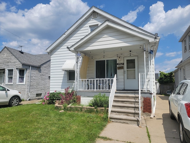 bungalow-style home featuring covered porch and a front yard