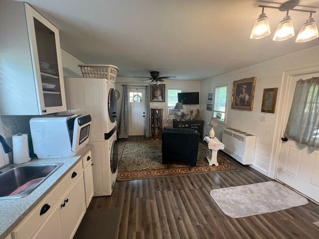 kitchen with radiator, ceiling fan, stacked washer and dryer, white cabinetry, and dark hardwood / wood-style floors