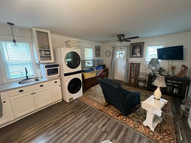 laundry room with stacked washer / dryer, ceiling fan, sink, and dark hardwood / wood-style floors