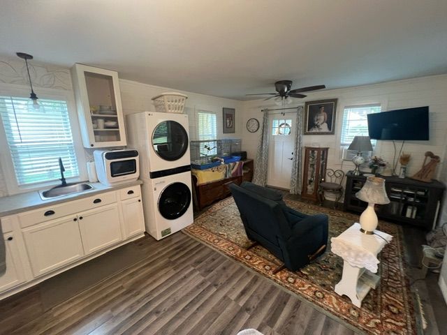 7153 Cedar Rd, Lexington, MI 48450 - living area with ceiling fan, stacked washing maching and dryer, a healthy amount of sunlight, and dark wood-type flooring
