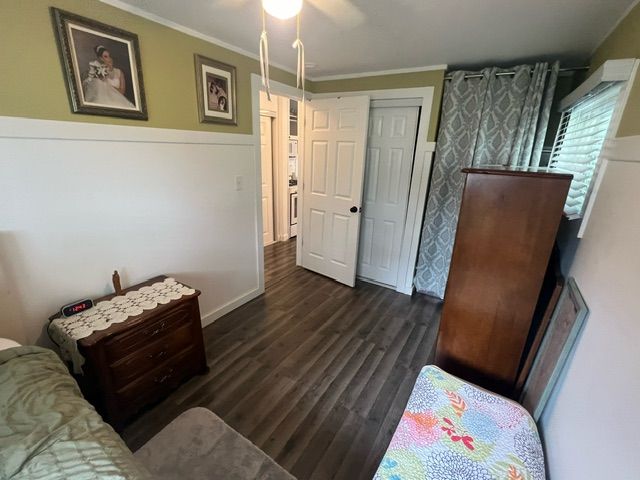 bedroom featuring ceiling fan, a closet, crown molding, and dark hardwood / wood-style floors