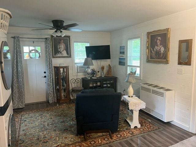 living room featuring heating unit, plenty of natural light, dark wood-type flooring, and ceiling fan