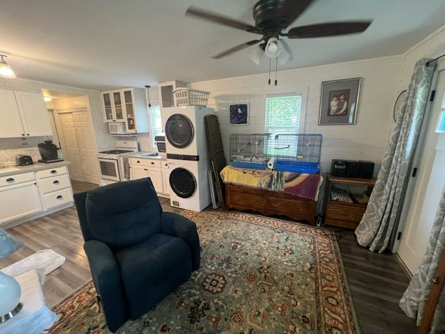 interior space with ornamental molding, stacked washing maching and dryer, and wood-type flooring