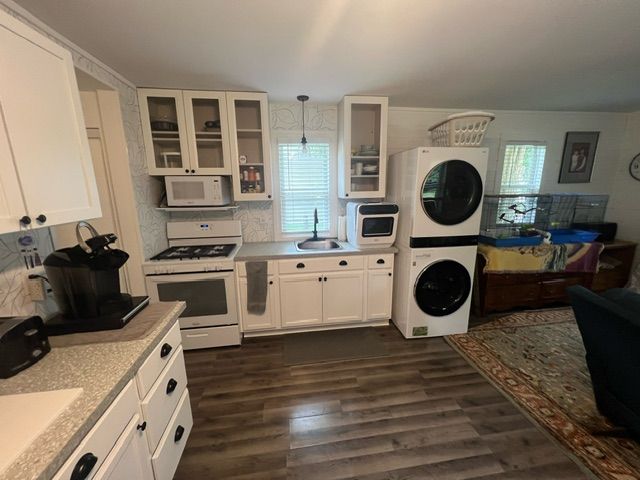 kitchen featuring white appliances, decorative light fixtures, plenty of natural light, and stacked washer and clothes dryer