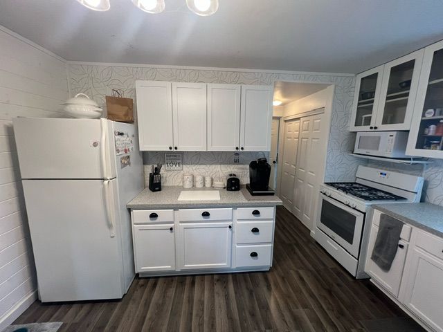 kitchen featuring wood walls, white cabinetry, dark hardwood / wood-style flooring, and white appliances