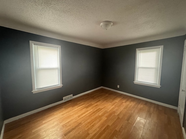 spare room with light hardwood / wood-style floors and a textured ceiling